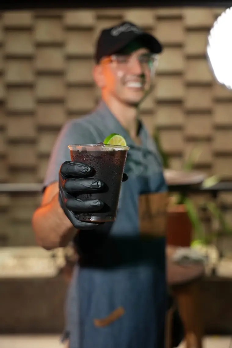 Barista ofreciendo una bebida fría con limón